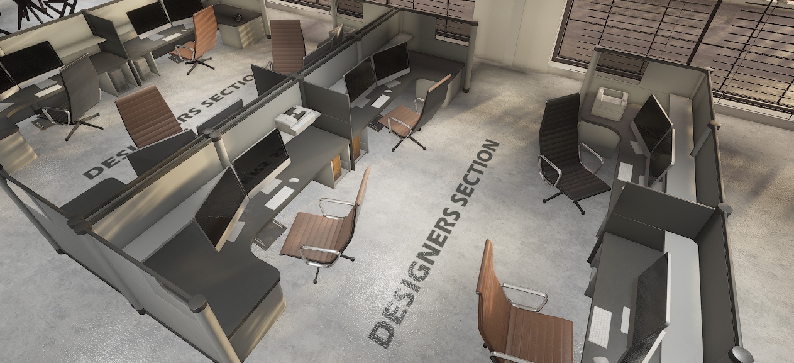 Top-down closeup of cubicle workstations with monitors and bold designers section floor text